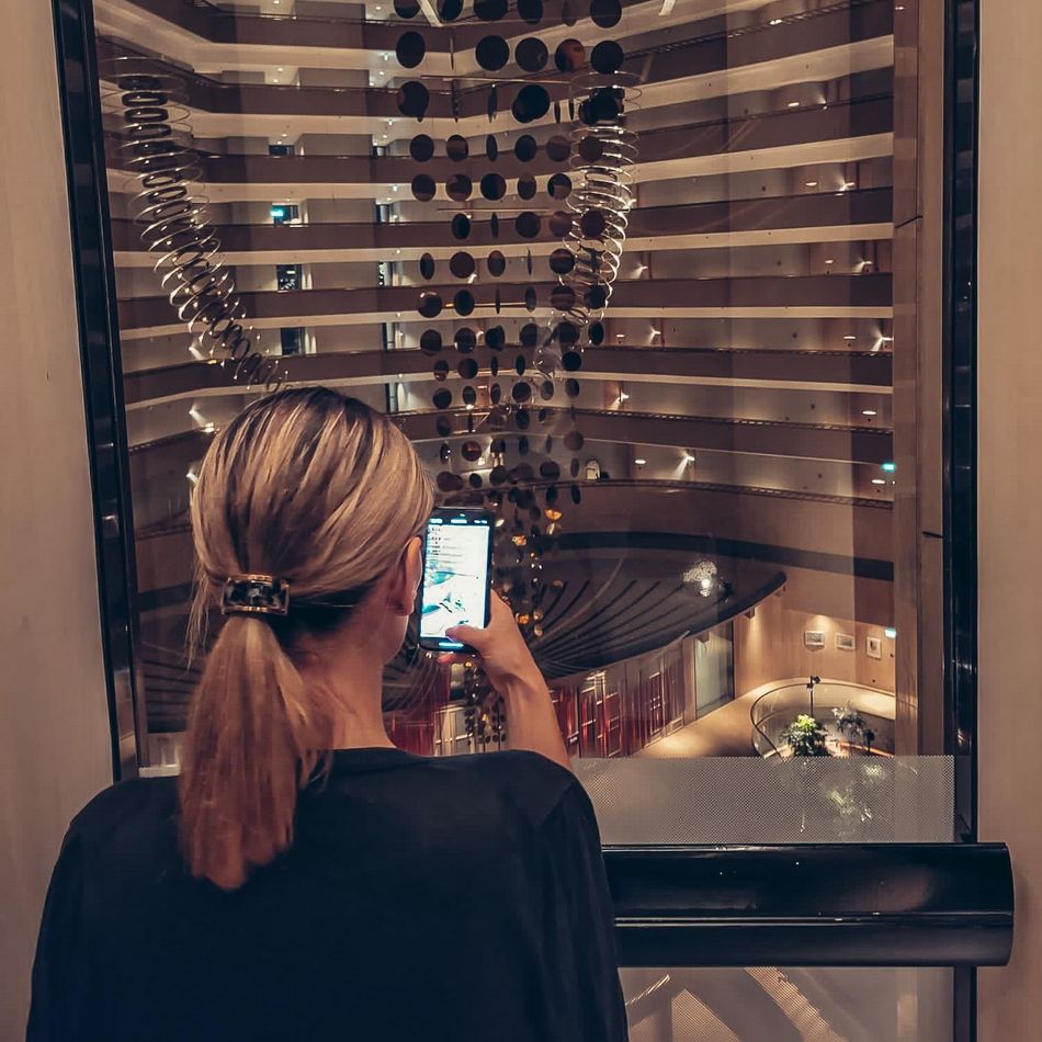 Frau fotografiert mit ihrem Handy die Hotellobby des Parkroyal Collection in Singapur.