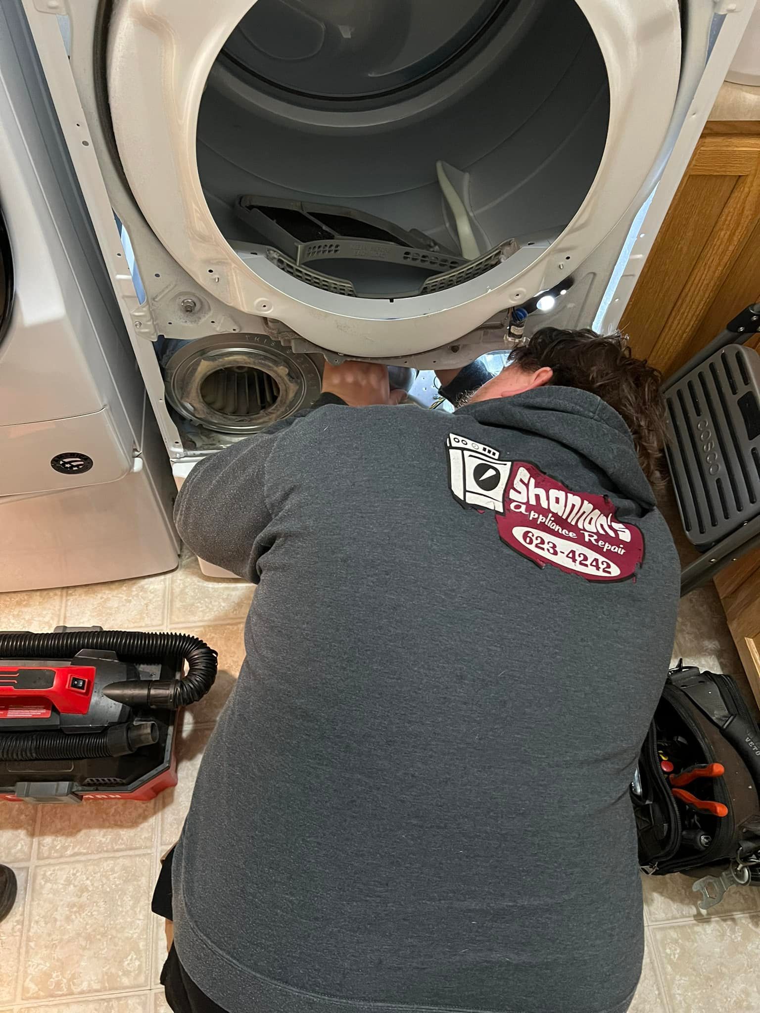 A man is working on a washer and dryer in a laundry room.