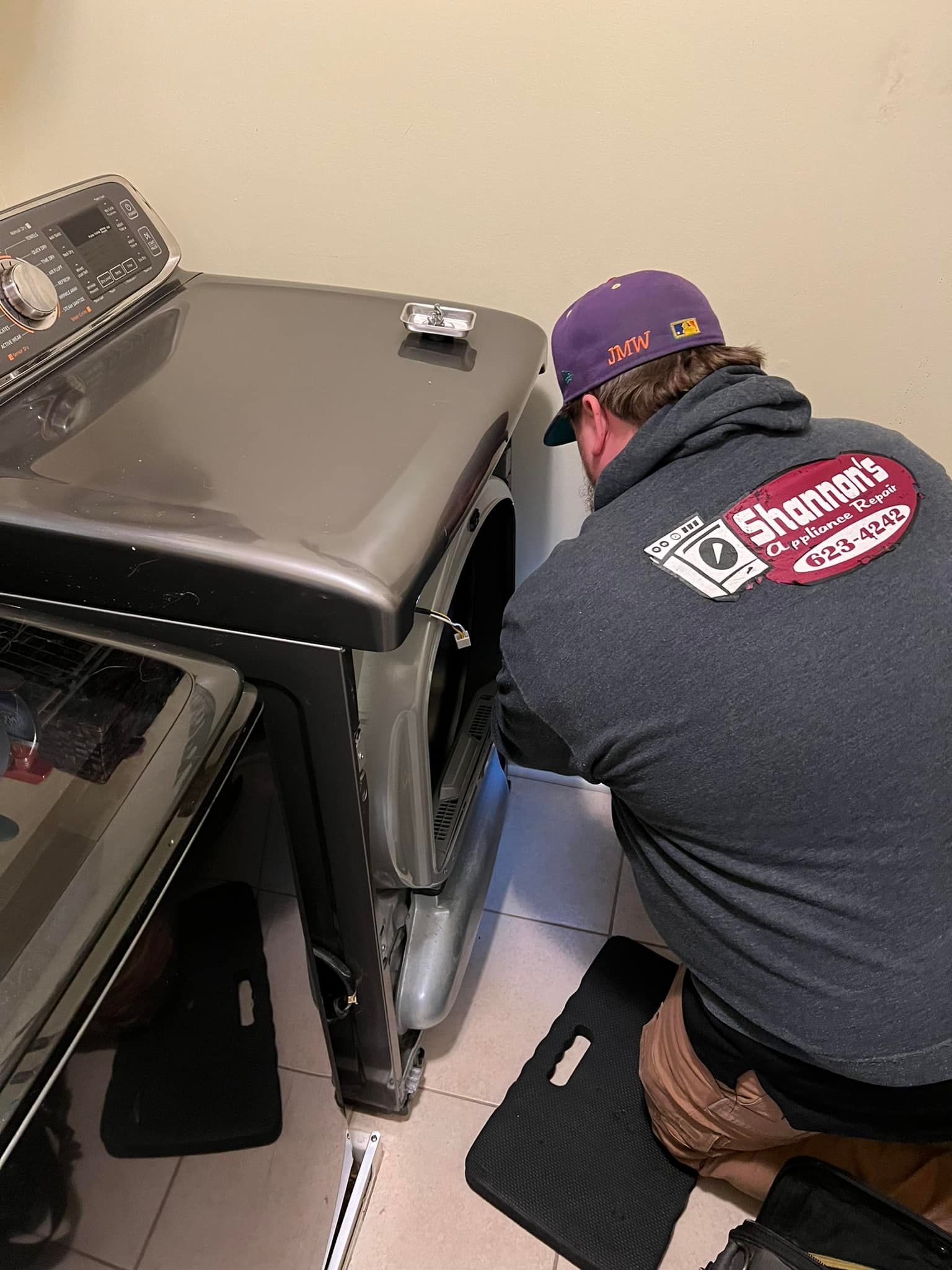 A man is working on a washing machine in a laundry room.