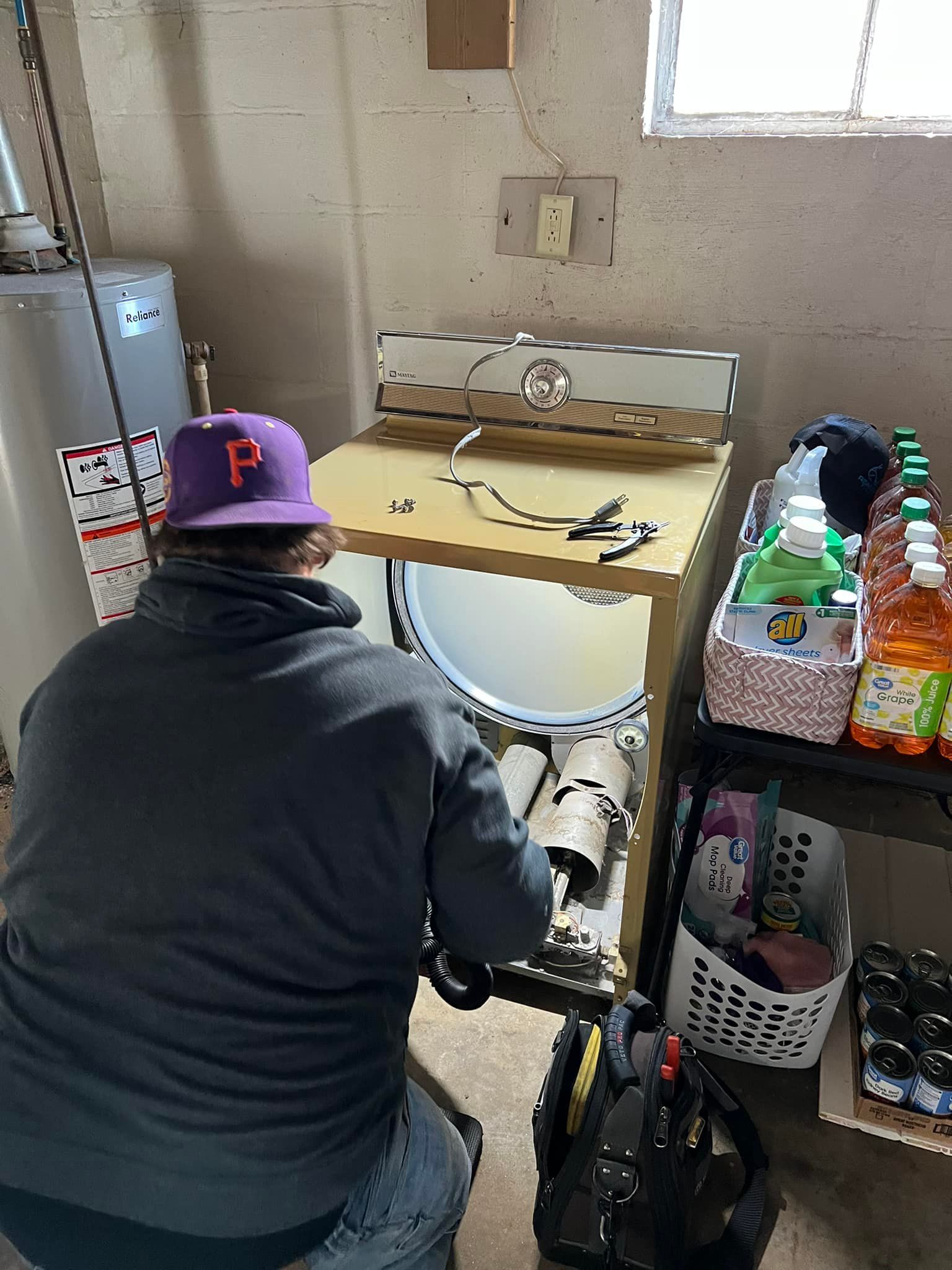 A man is working on a washing machine in a room.