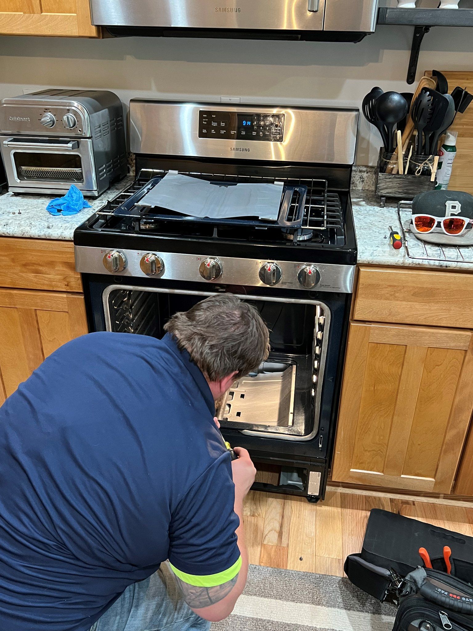 A man is working on a stove in a kitchen.