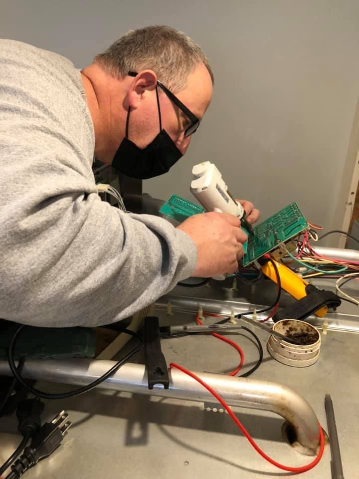 A man wearing a mask is working on a piece of electronic equipment.