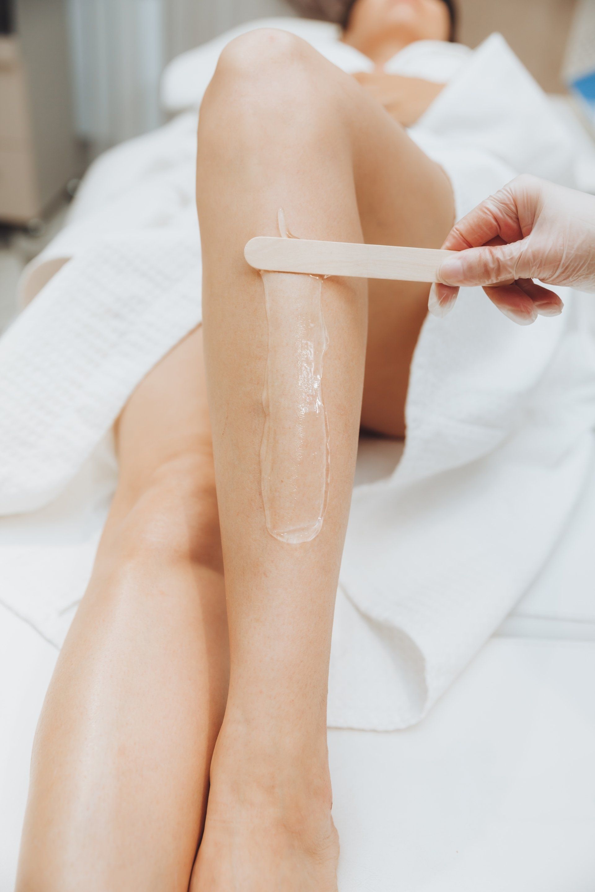 cosmetologist puts a gel for laser hair removal on leg