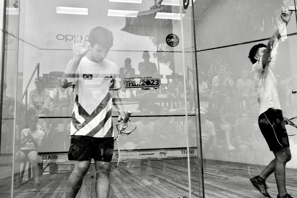 Dois homens estão jogando squash em uma foto em preto e branco.
