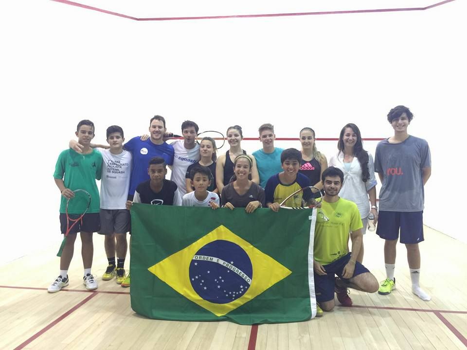 Um grupo de pessoas posando para uma foto com uma bandeira brasileira