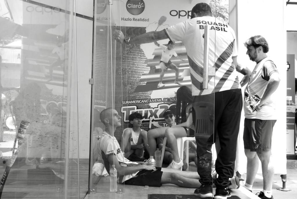 Um grupo de pessoas está sentado em frente a uma parede de vidro.