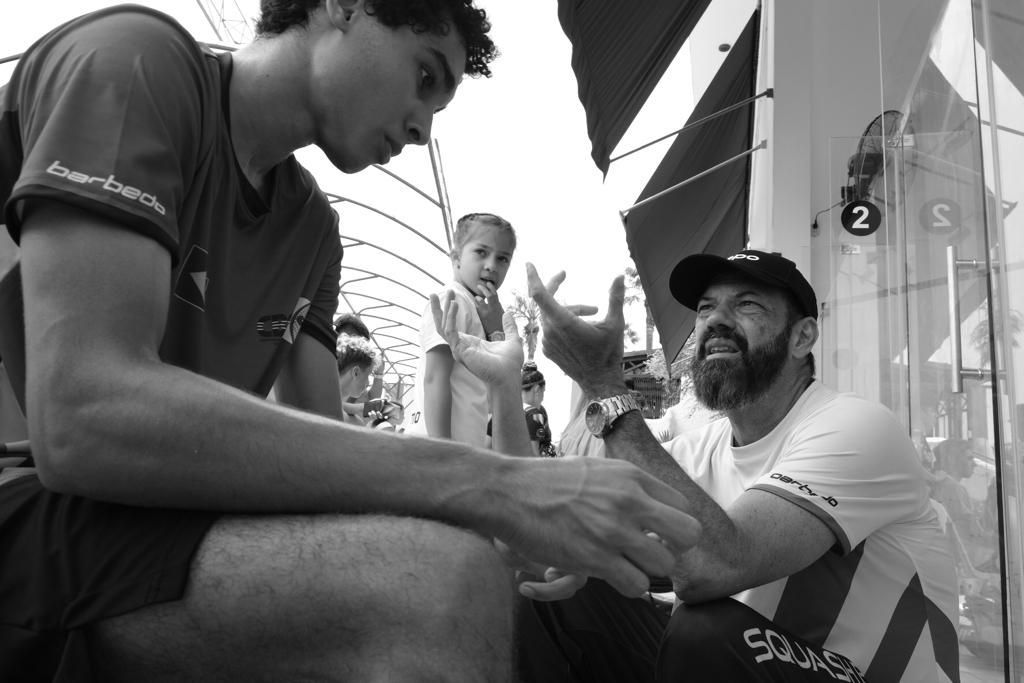 Dois homens apertam as mãos em uma foto em preto e branco.