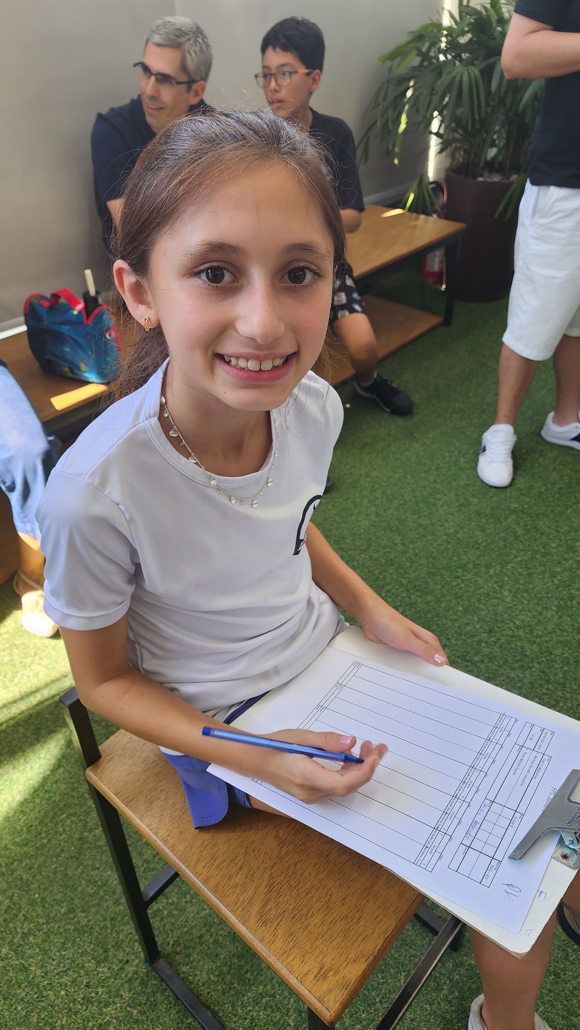 Uma jovem está sentada em uma mesa com uma caneta na mão.