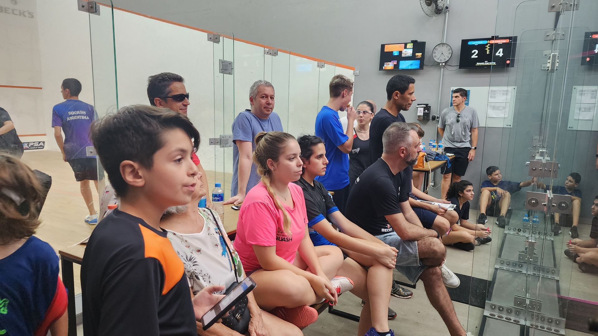 Um grupo de pessoas está sentado em uma academia assistindo a um jogo.