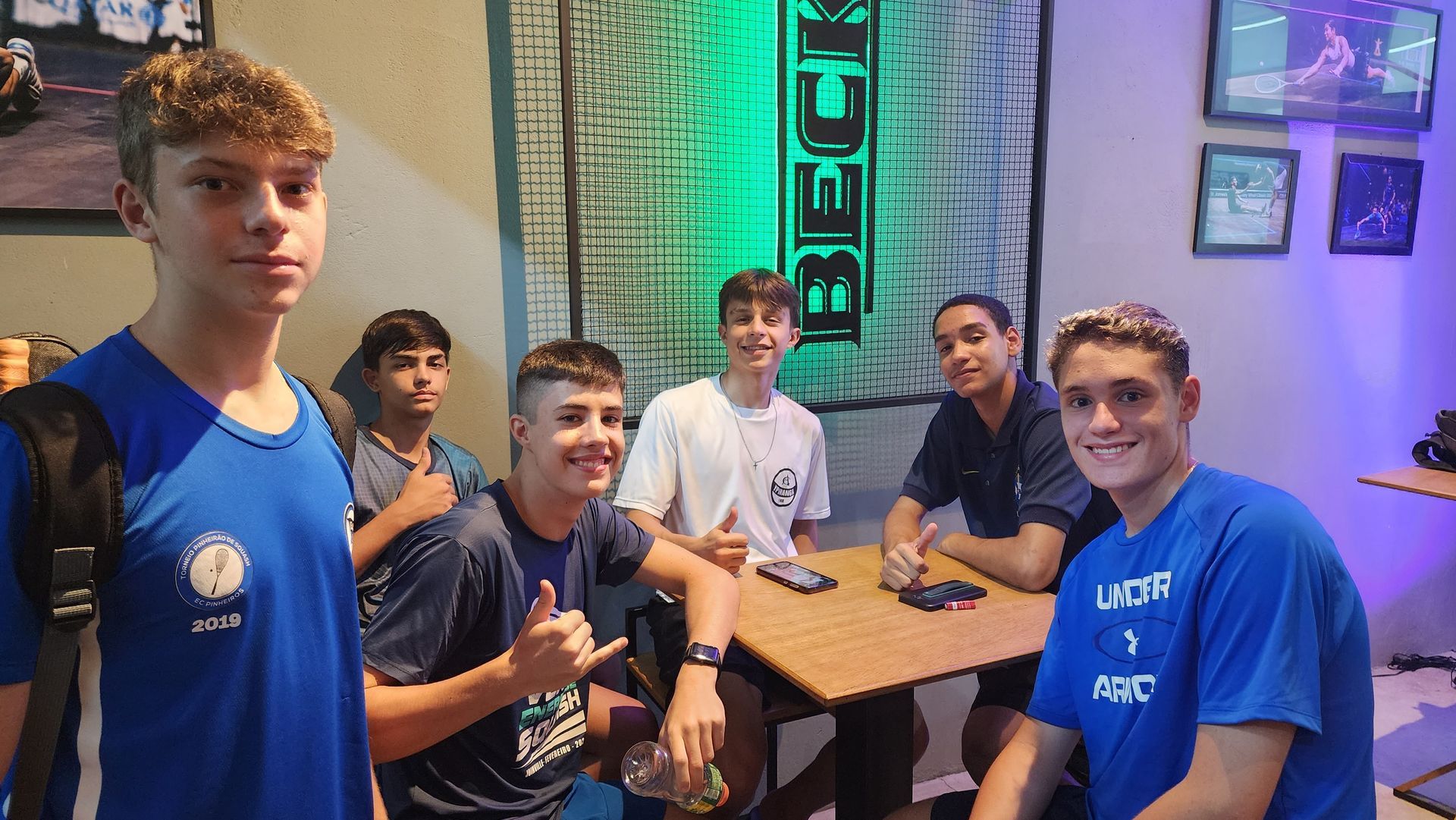 Um grupo de jovens está posando para uma foto em uma sala.