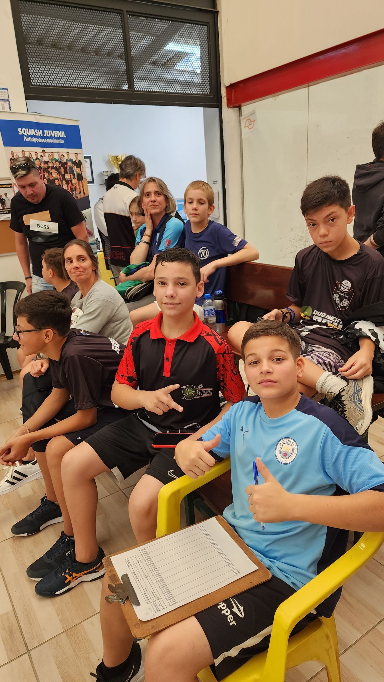 Um grupo de crianças está sentado em cadeiras e fazendo sinal de positivo.