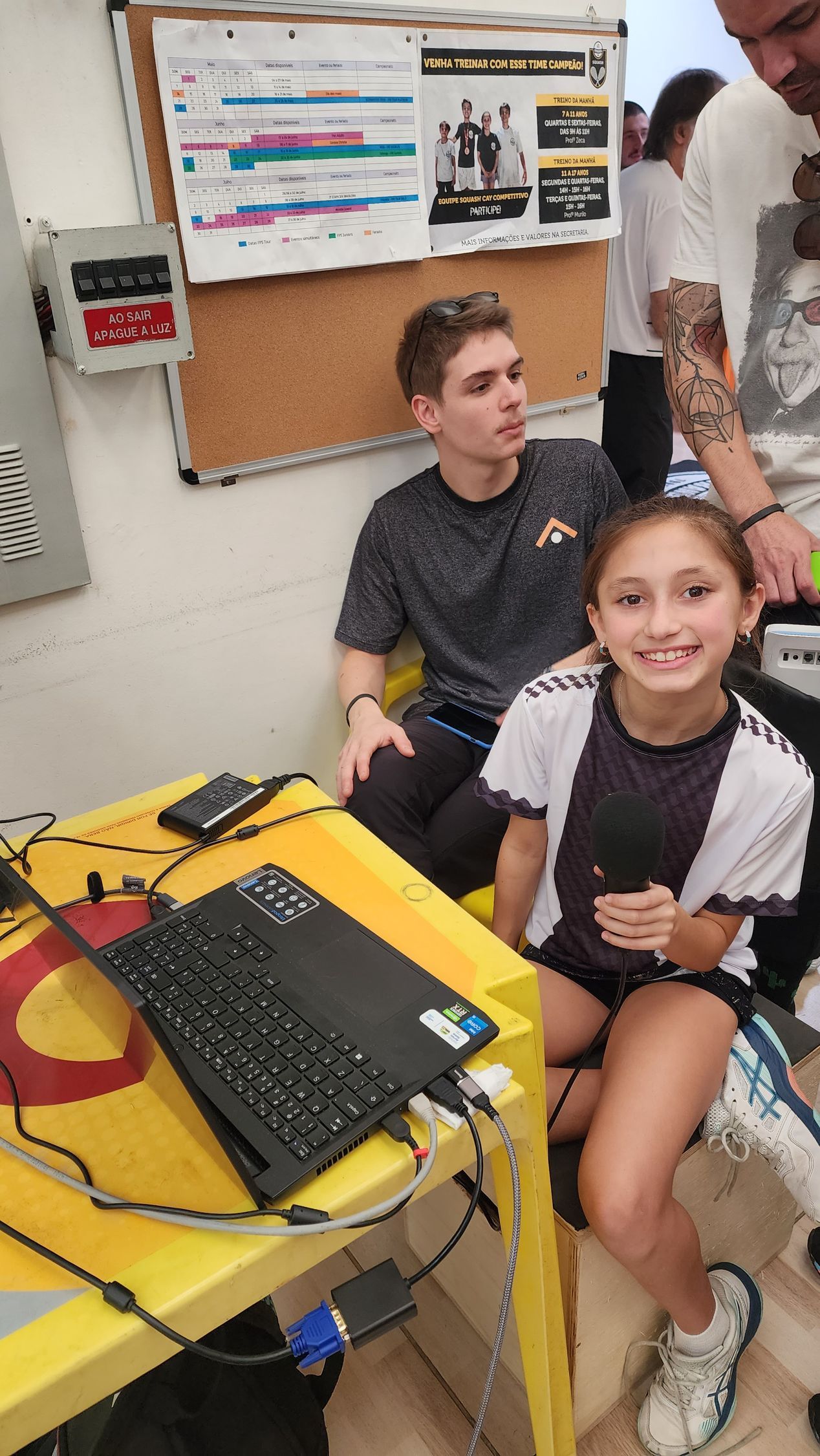 Um homem e uma menina estão sentados à mesa com um laptop.