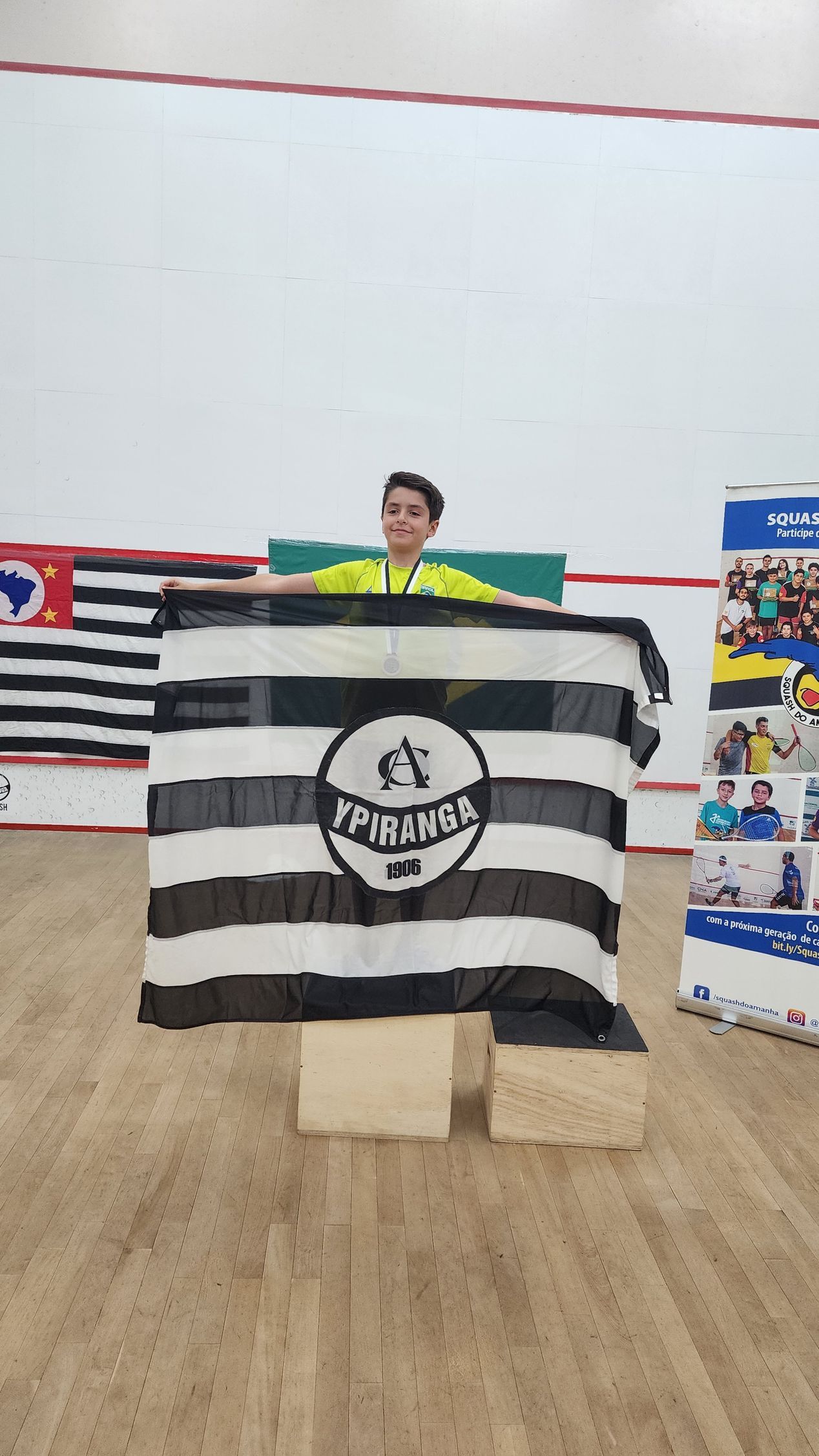 Um homem está segurando uma bandeira listrada de preto e branco em um ginásio.