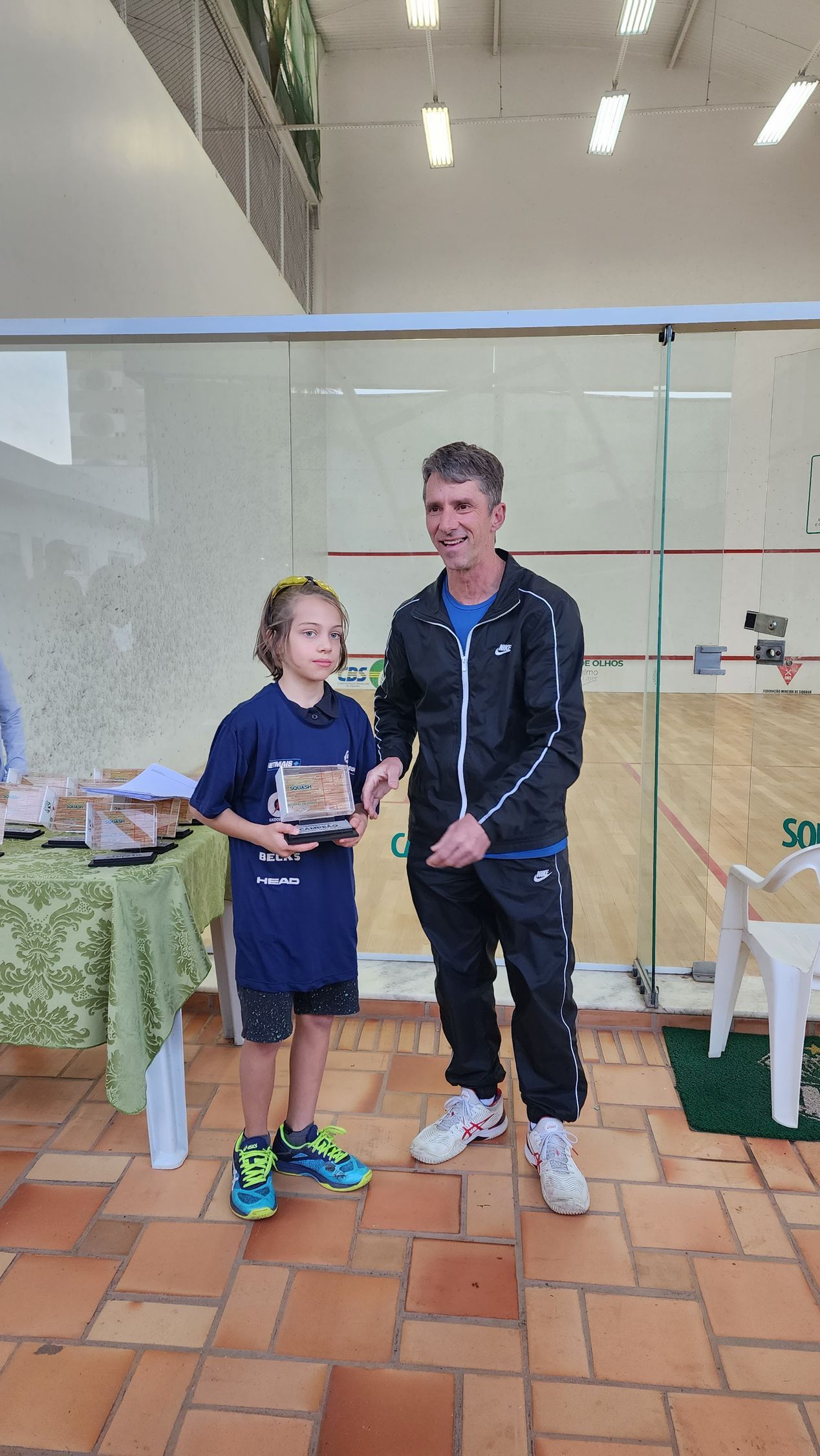 Um homem está de pé ao lado de um menino segurando um troféu.