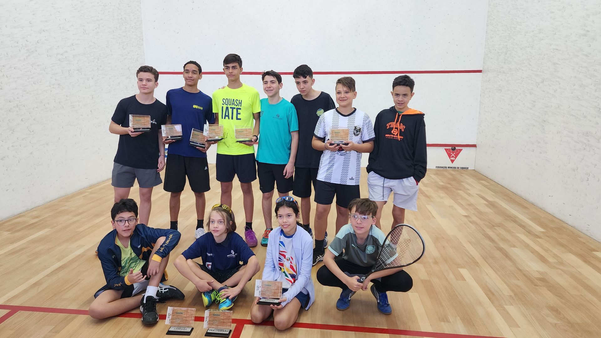 Um grupo de jovens está posando para uma foto em uma quadra de tênis.