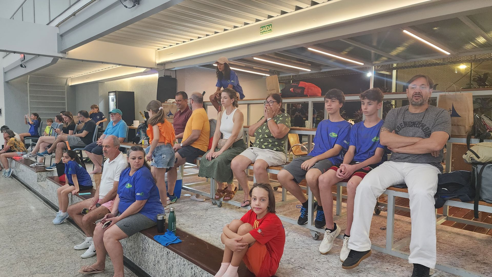 Um grupo de pessoas está sentado em um banco assistindo a um jogo.