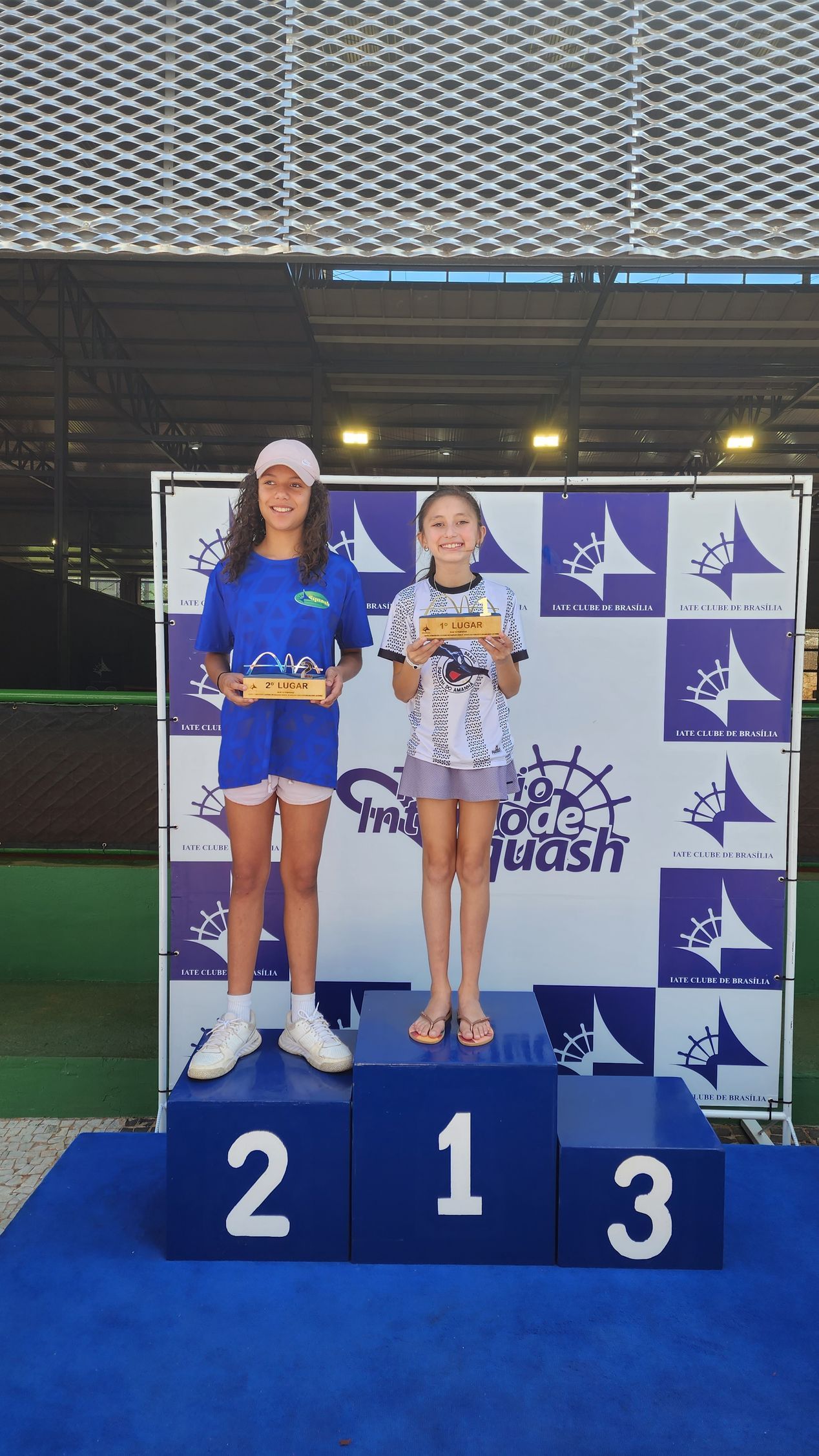 Duas meninas em pé em um pódio com o número 213 nele