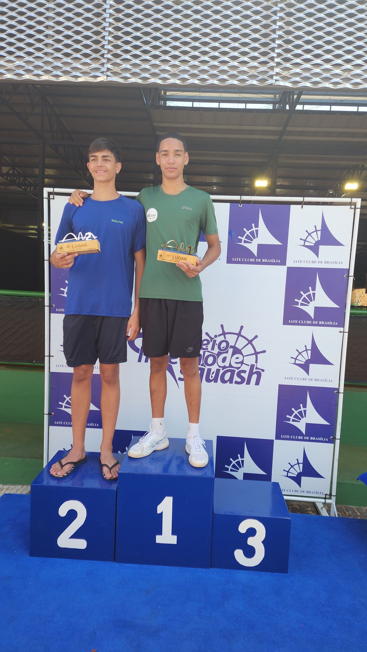 Dois meninos em pé em um pódio com o número 213 nele