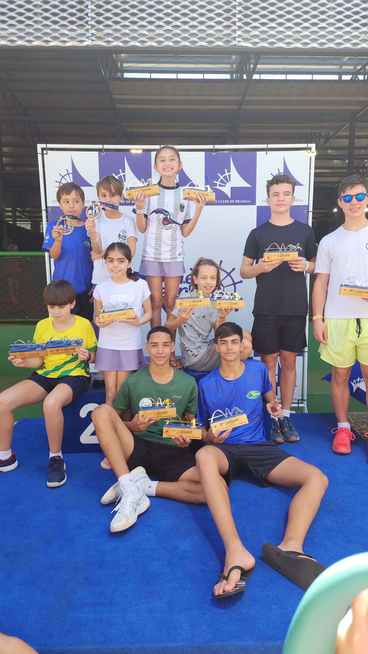 Um grupo de crianças está posando para uma foto enquanto segura troféus.