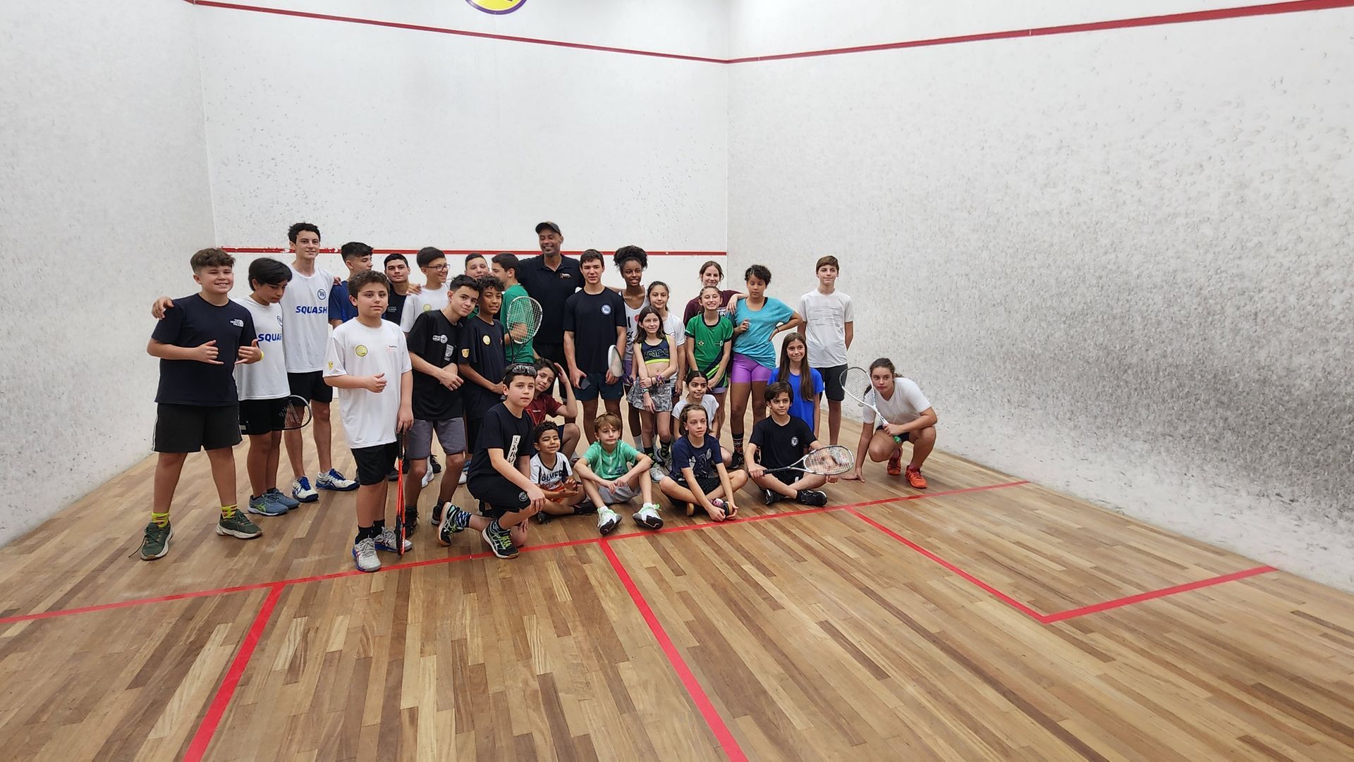 um grupo de pessoas posa para uma foto em uma quadra de squash.