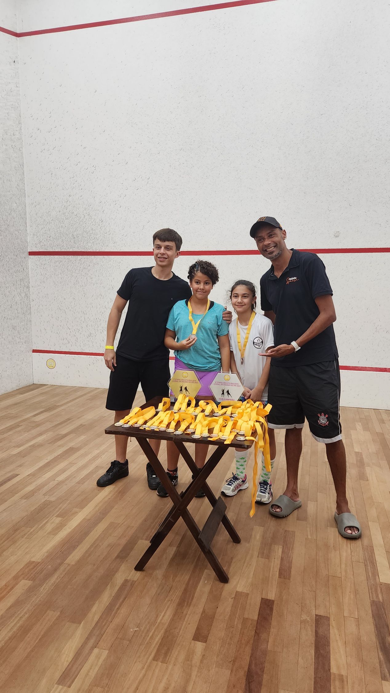 um grupo de pessoas posa para uma foto em uma quadra de squash.