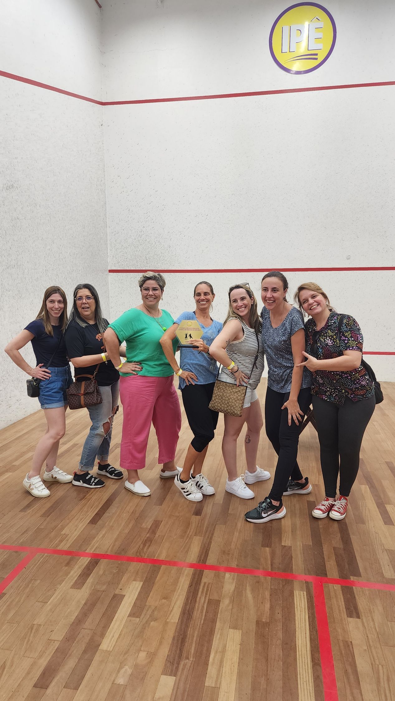 um grupo de mulheres posa para uma foto em uma quadra de squash.