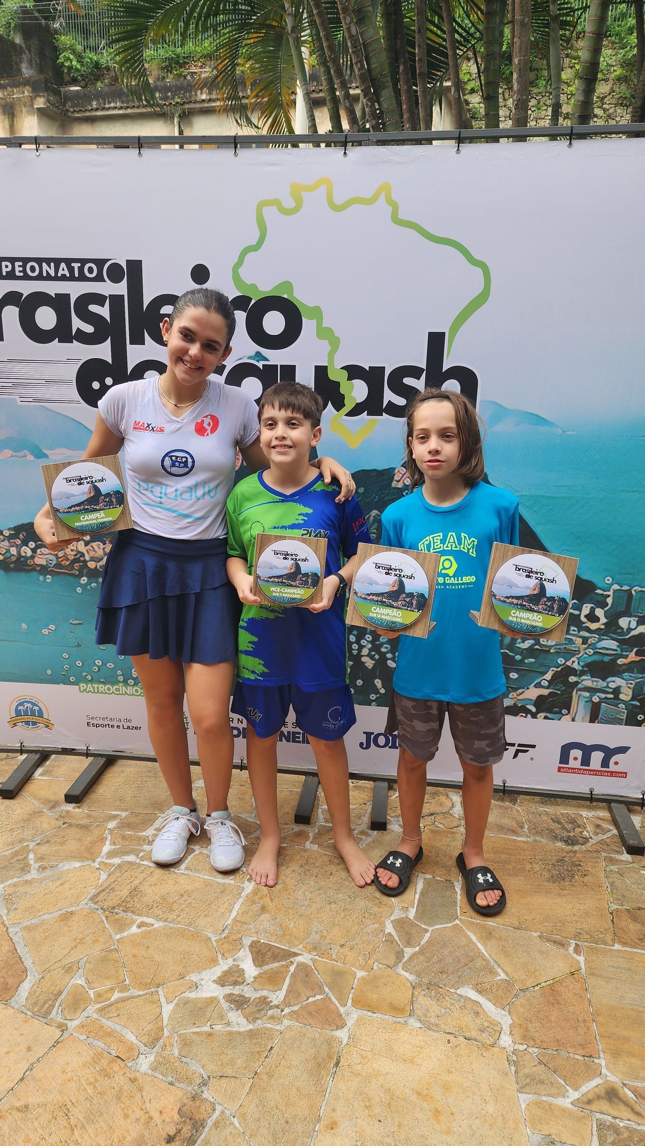 uma mulher e duas crianças estão lado a lado segurando troféus.