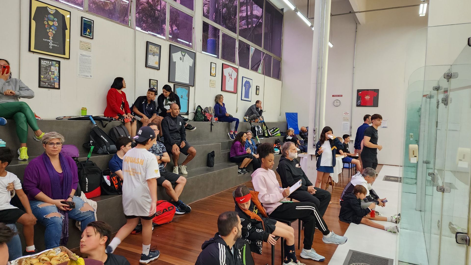 Um grupo de pessoas está sentado nas arquibancadas de um ginásio.