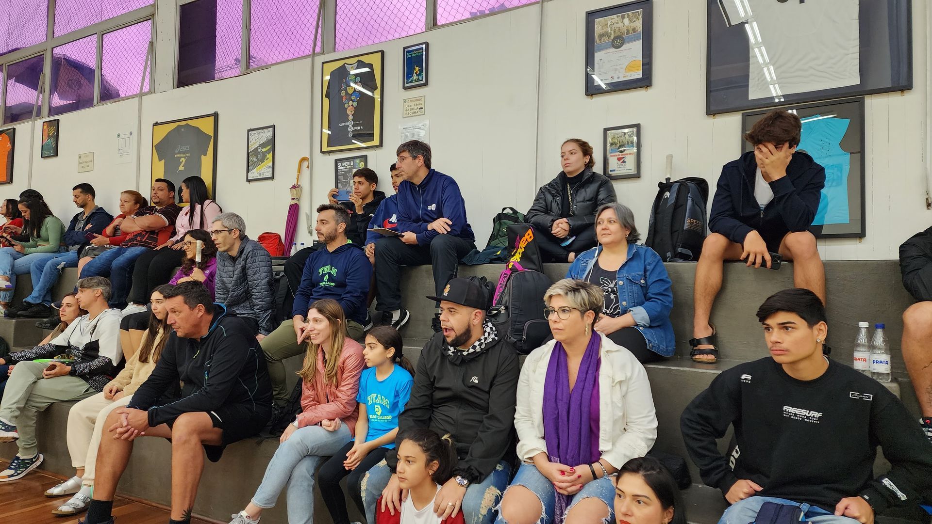 Um grupo de pessoas está sentado nas arquibancadas assistindo a um jogo.