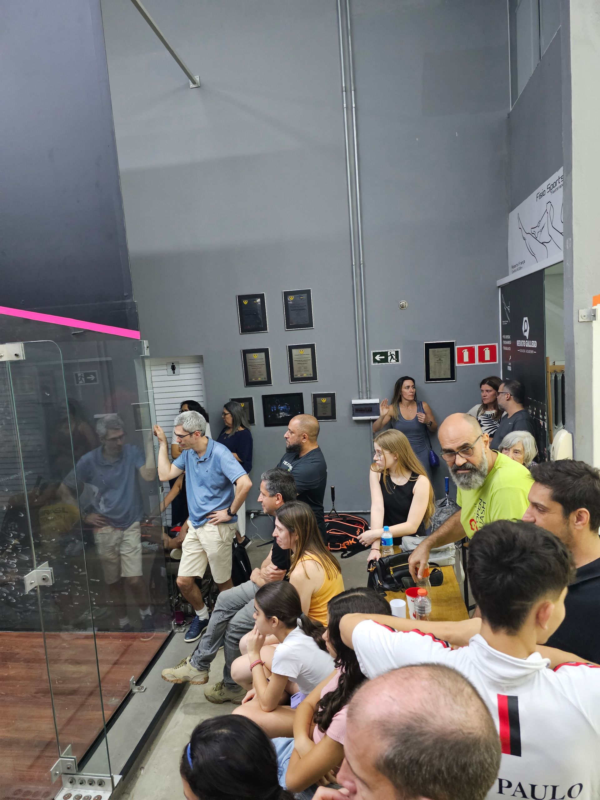 Um grupo de pessoas está sentado em uma sala com um extintor de incêndio na parede.