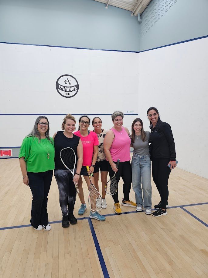 Um grupo de mulheres está posando para uma foto em uma quadra de tênis.