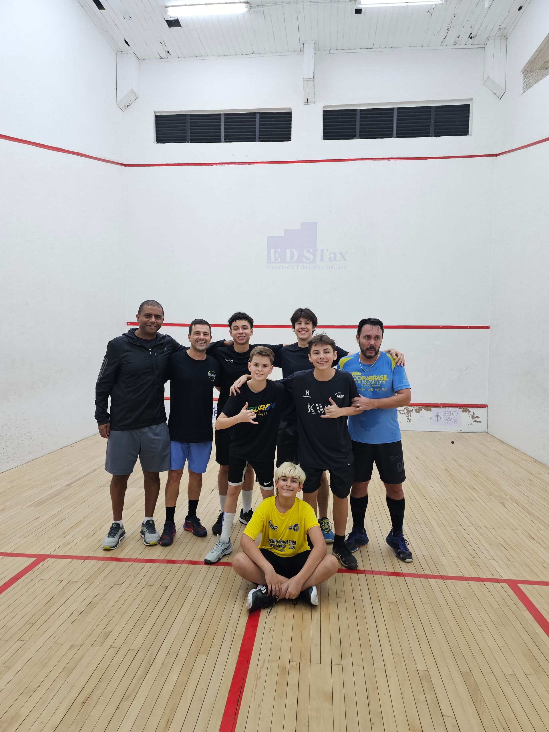Um grupo de pessoas posando para uma foto em uma quadra de squash