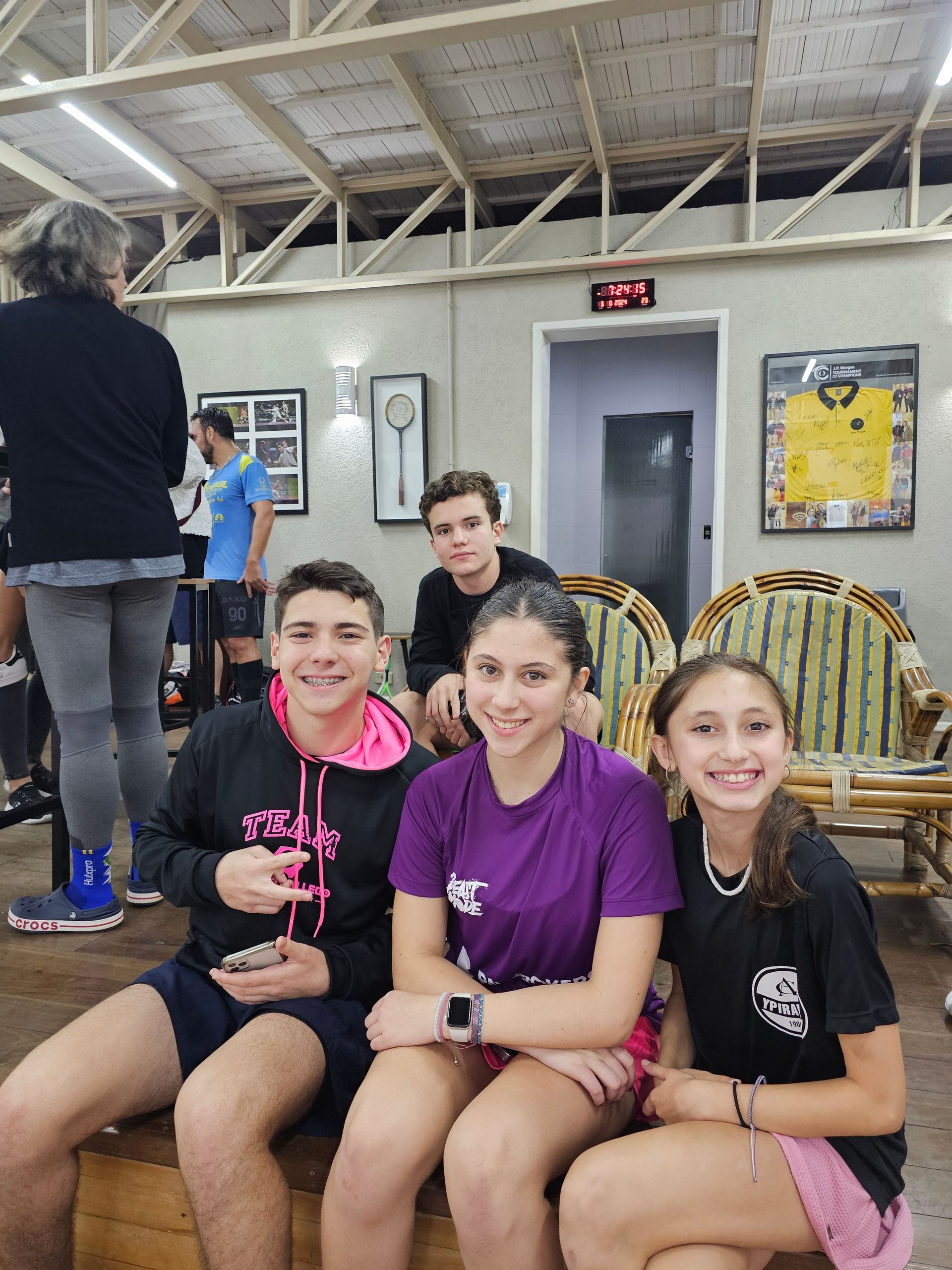 Um grupo de jovens está sentado em um banco em uma sala.