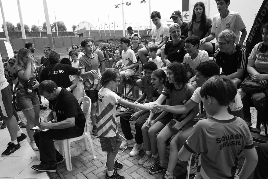 Um grupo de pessoas está sentado em cadeiras e apertando as mãos.