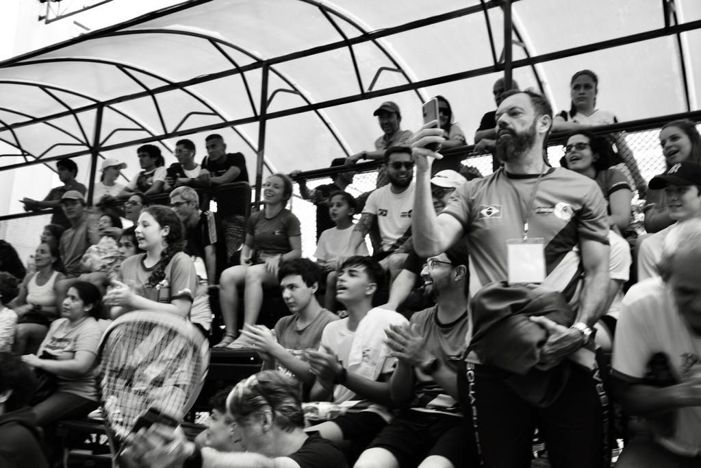 Uma foto em preto e branco de uma multidão assistindo a uma partida de tênis.