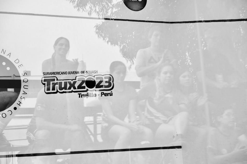 um grupo de pessoas está sentado em frente a uma placa que diz truc23