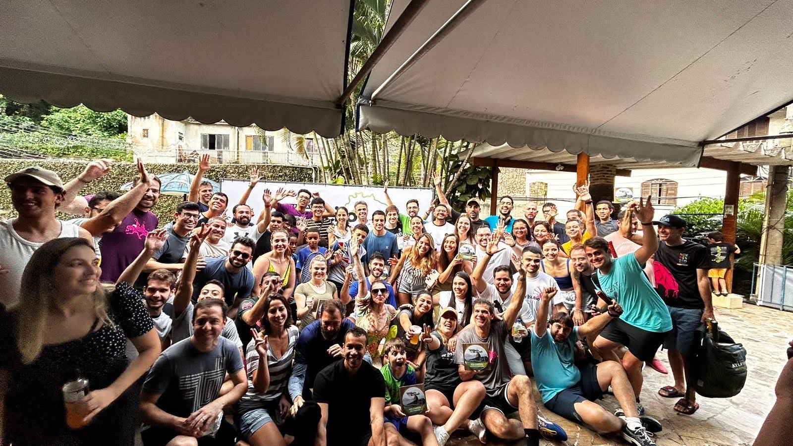 Um grande grupo de pessoas está posando para uma foto sob uma barraca.