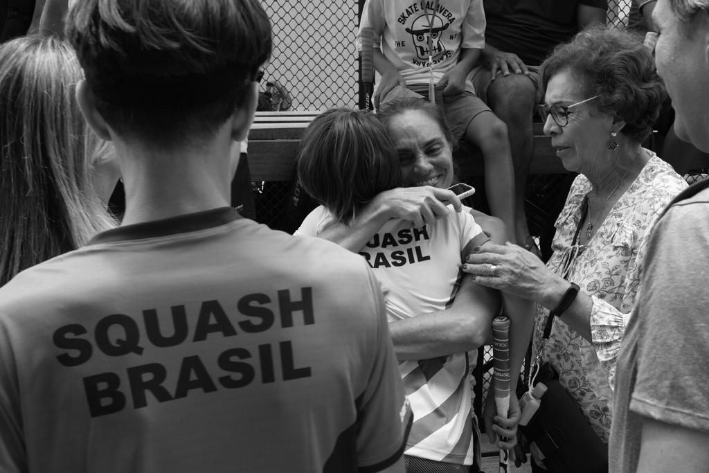 Uma pessoa vestindo uma camisa do squash brasil está abraçando outra pessoa.