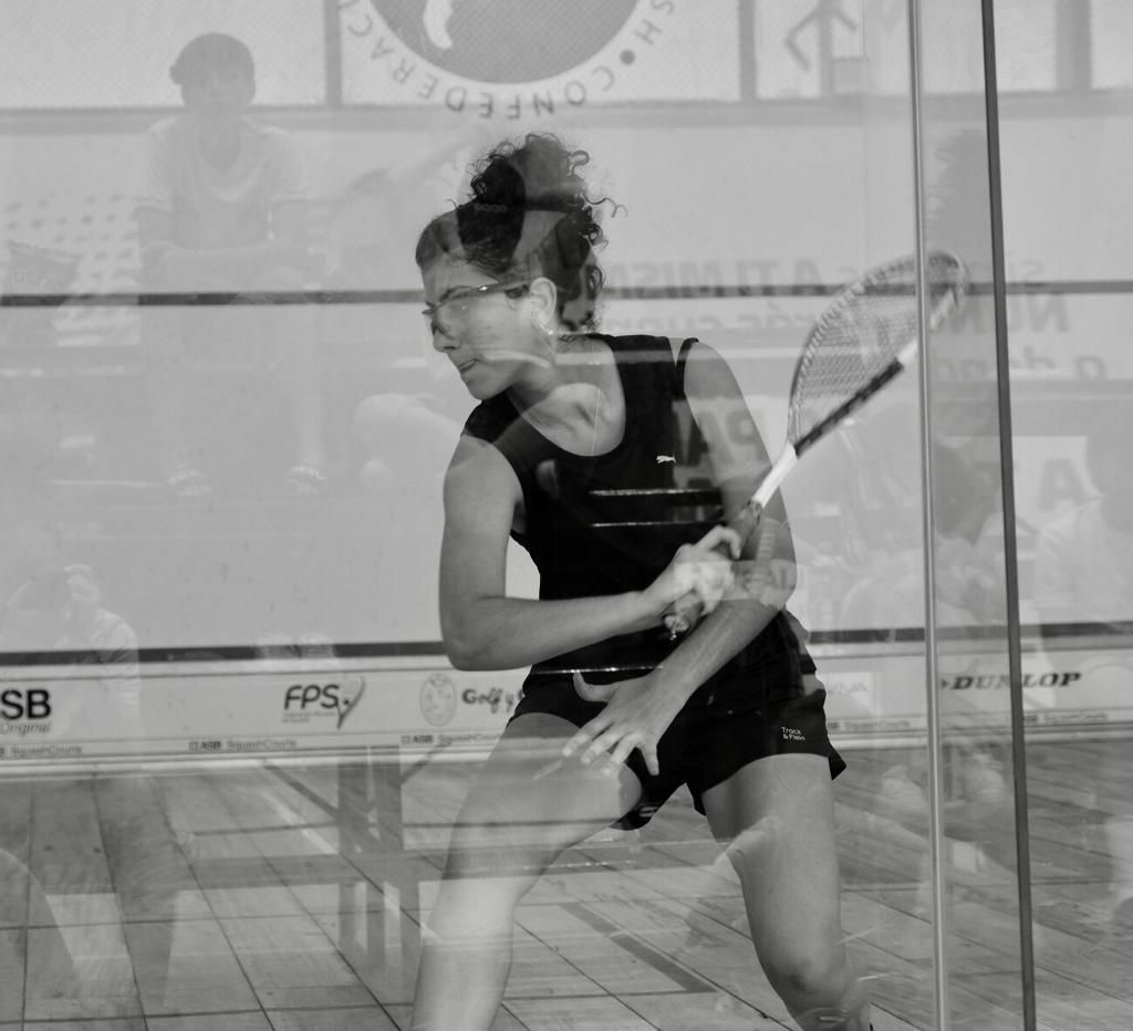 Uma foto em preto e branco de uma mulher jogando squash