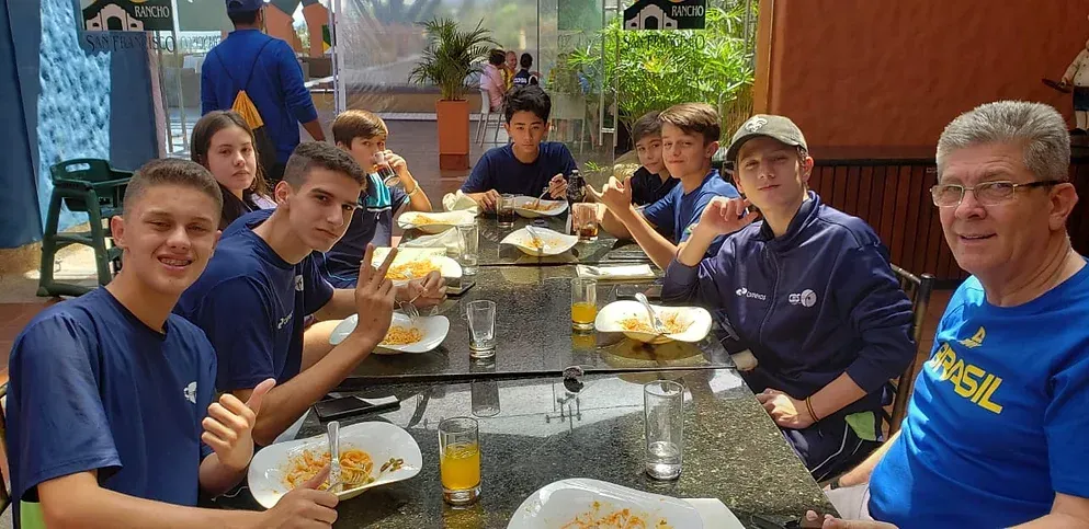 Um grupo de pessoas está sentado à mesa comendo.