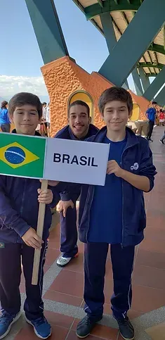 Três garotos estão segurando uma placa que diz brasil.