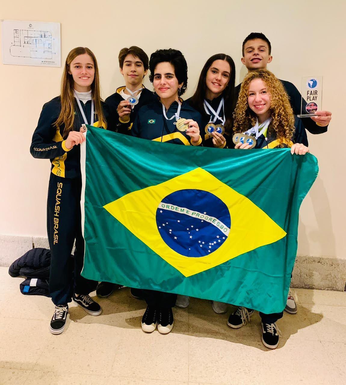 um grupo de pessoas segurando uma bandeira e medalhas