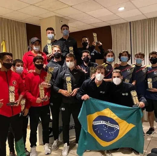 Um grupo de pessoas usando máscaras faciais segurando troféus e uma bandeira