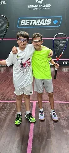 Dois meninos estão posando para uma foto em uma quadra de squash.