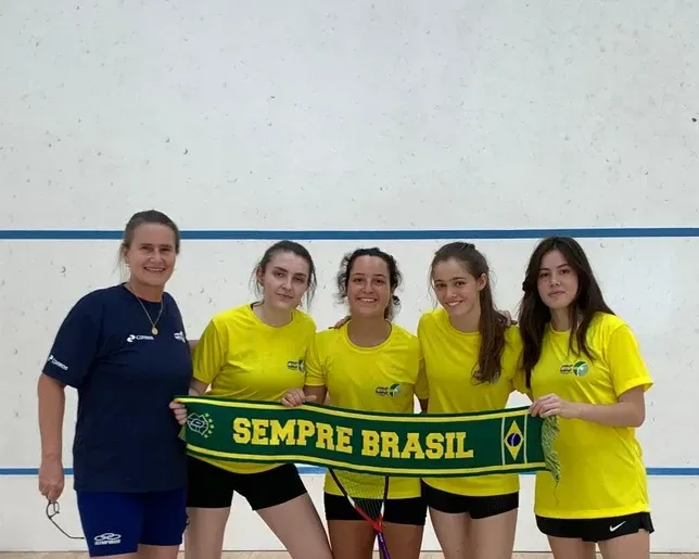 Um grupo de meninas segurando um cachecol que diz sempre brasil