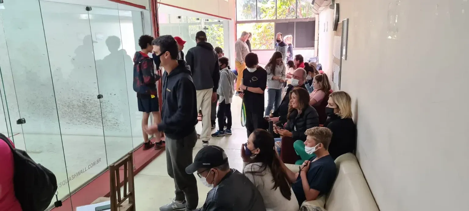 Um grupo de pessoas está de pé e sentada em um corredor.