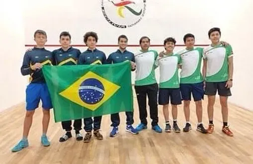 Um grupo de jovens posa para uma foto segurando uma bandeira brasileira.