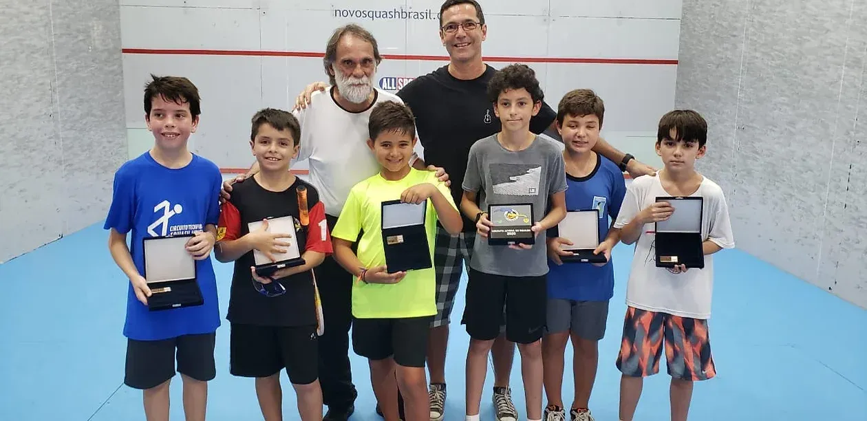 Um grupo de jovens rapazes posa para uma foto segurando troféus.