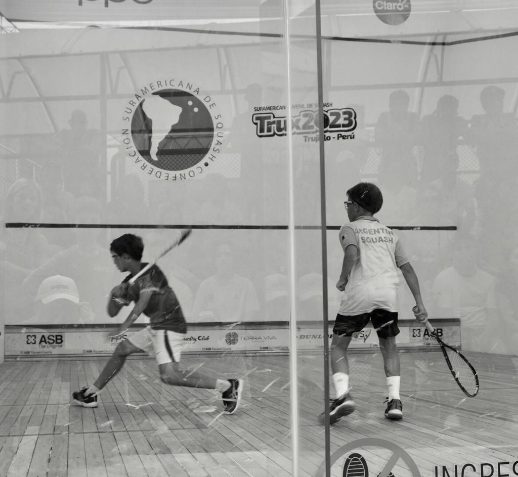 Uma foto em preto e branco de dois meninos jogando squash