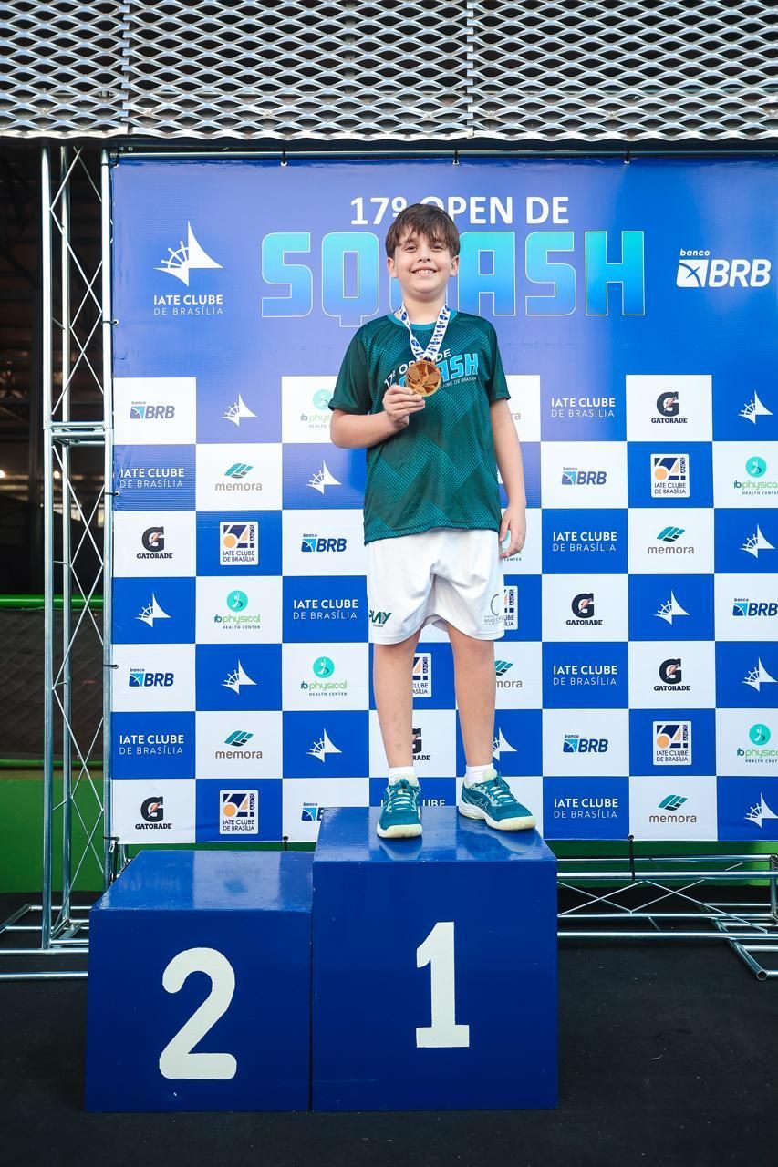 Um menino está em um pódio com o número 21 nele